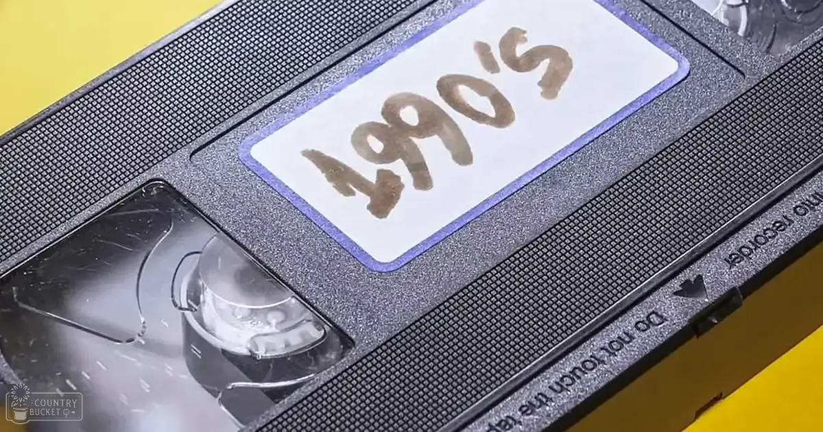 Close-up shot of a worn 1990s VHS tape with 'Do not touch the' text on it, set against a solid yellow indoor background.