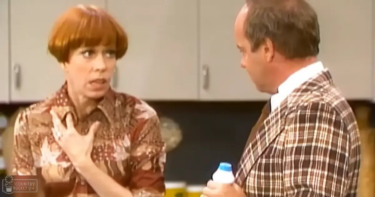 Adult female in a fitted floral shirt indoors, interacting with an adult male holding a small bottle; kitchen setting suggests domestic scene.