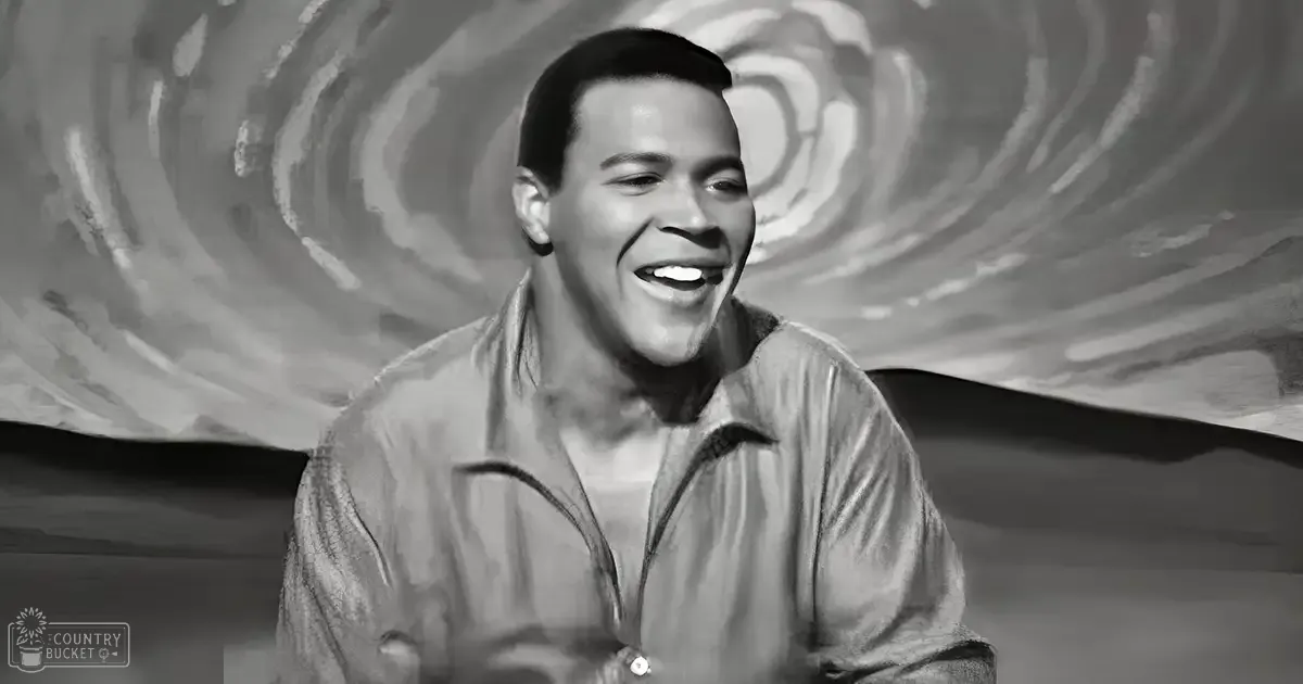 A young adult male wearing a light-colored collared shirt with a textured appearance, set against an abstract monochromatic background.
