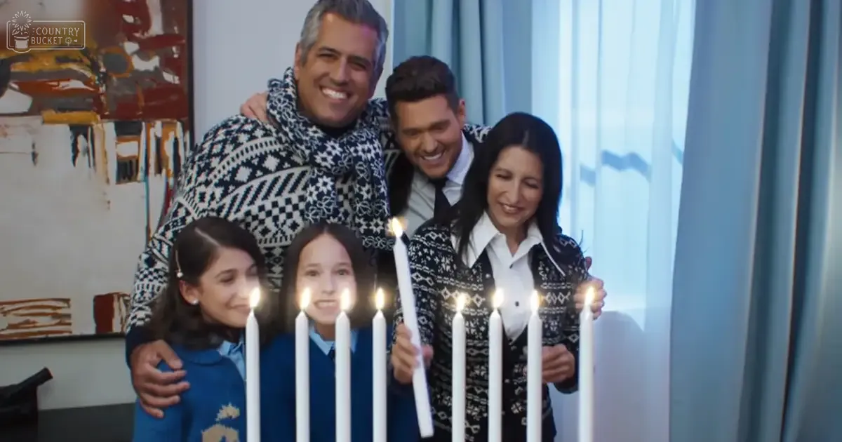 A family celebrating with candles indoors during winter; adults wear patterned sweaters and children in blue uniforms.