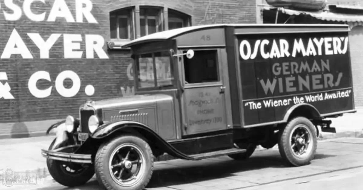 Oscar Mayer Wienermobile truck advertising German Wieners parked on a city street with brick buildings and 'Oscar Mayer & Co.' signage.