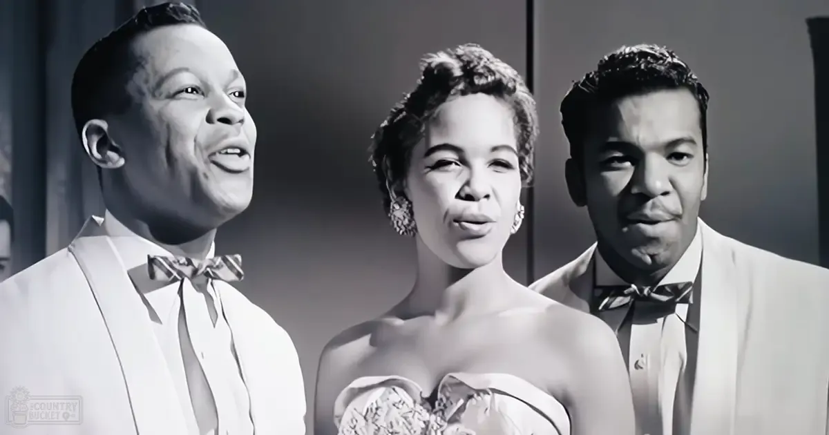 A group portrait from the mid-20th century with three individuals dressed in formal attire against a plain indoor background with even lighting.