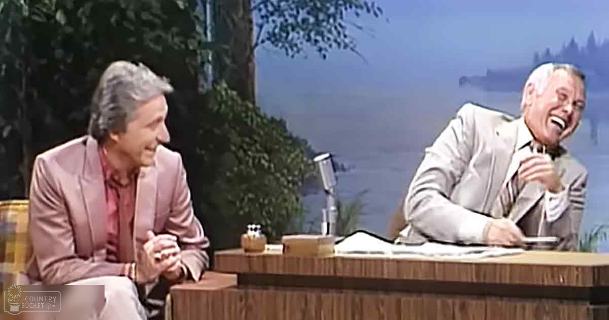 Two individuals engaged in conversation against a backdrop of trees and water, suggesting an outdoor setting within an indoor studio during spring or summer.