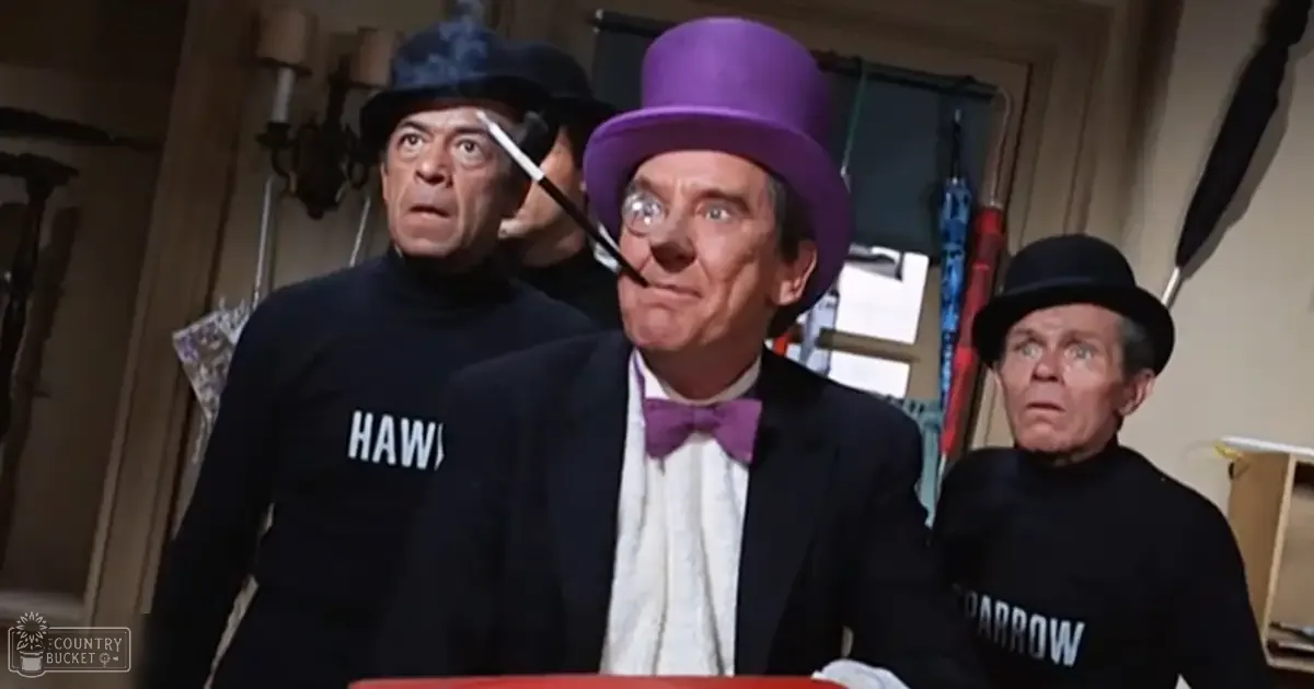 A man wearing a purple top hat and bow tie, smoking a pipe, stands indoors with two older men in black turtlenecks, also smoking pipes; red object at bottom unclear.