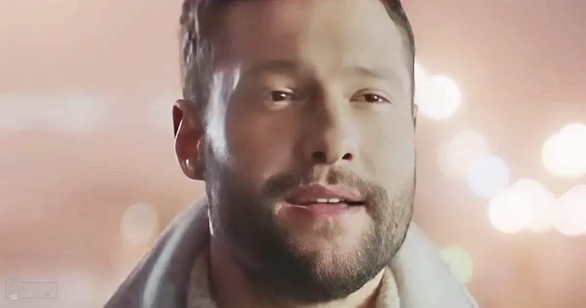 A middle-aged adult male wearing a light gray collared shirt in an urban evening setting.
