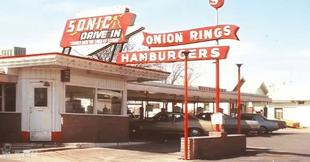 Sonic Drive-In restaurant exterior, vintage sedan parked in front of a clear-sky setting with bare trees indicating late fall or early spring.
