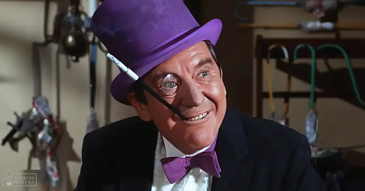 A middle-aged adult male wearing formal attire, including a top hat and suit, indoors with shelves in the background.