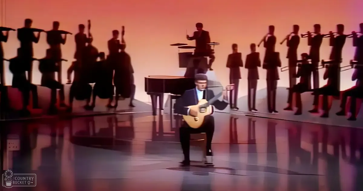 A musician plays an acoustic guitar on stage with a large orchestra at a concert venue under warm orange stage lights.