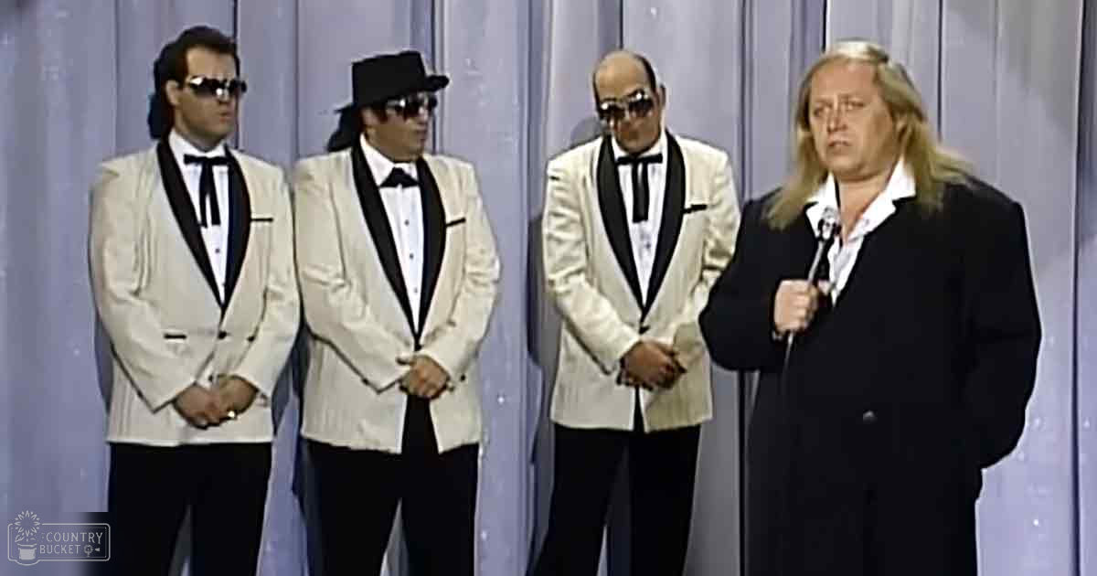 Four individuals in formal attire perform on stage with a simple backdrop and even lighting.
