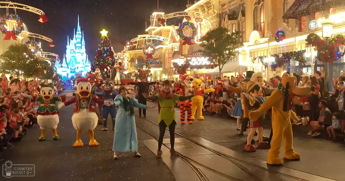 A vibrant nighttime scene at Disney World, Orlando, with festive decorations, characters like Donald Duck and Goofy, and a large Christmas tree with blue lighting in Main Street, U.S.A.