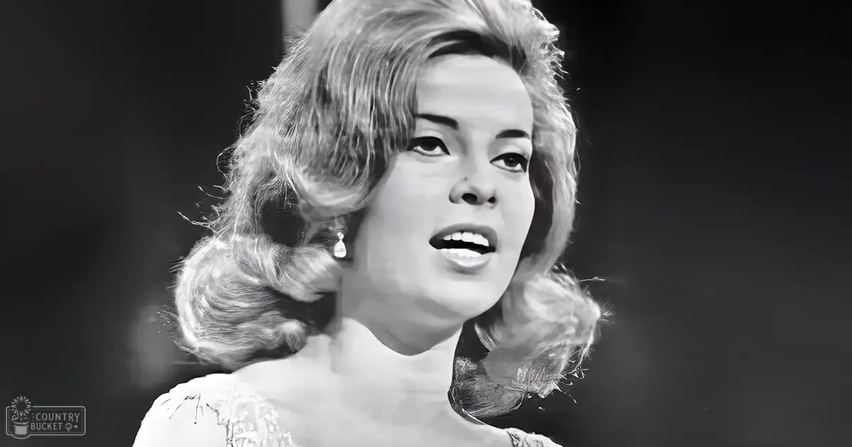 A young adult female in a fitted, lace-neckline garment with formal mid-20th century style, indoors at night.