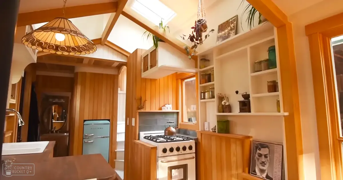 A cozy kitchen interior with a retro-style blue refrigerator, wooden cabinets, and natural light streaming in through a skylight.