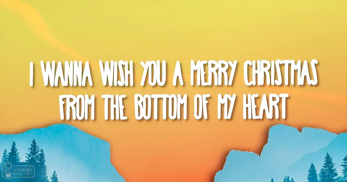 Abstract digital Christmas greeting with gradient yellow and orange hues, silhouettes of trees at bottom edges, text reading 'I WANNA WISH YOU A MERRY CHRISTMAS FROM THE BOTTOM OF MY HEART' displayed prominently in white font.