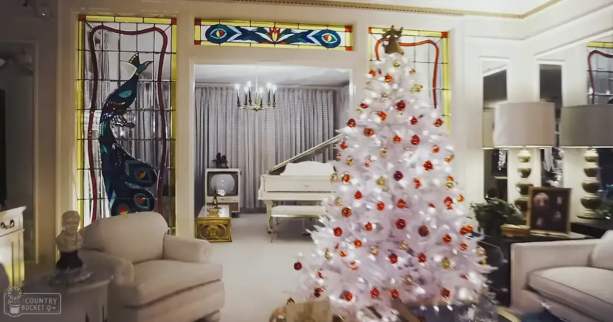 A decorated living room with a white Christmas tree, stained glass peacocks, and vintage furniture during winter evening light.