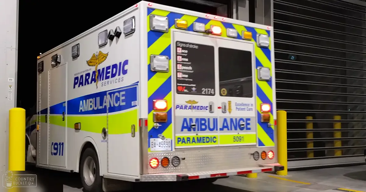 An ambulance parked inside a garage with emergency lights on top and reflective stripes for visibility.
