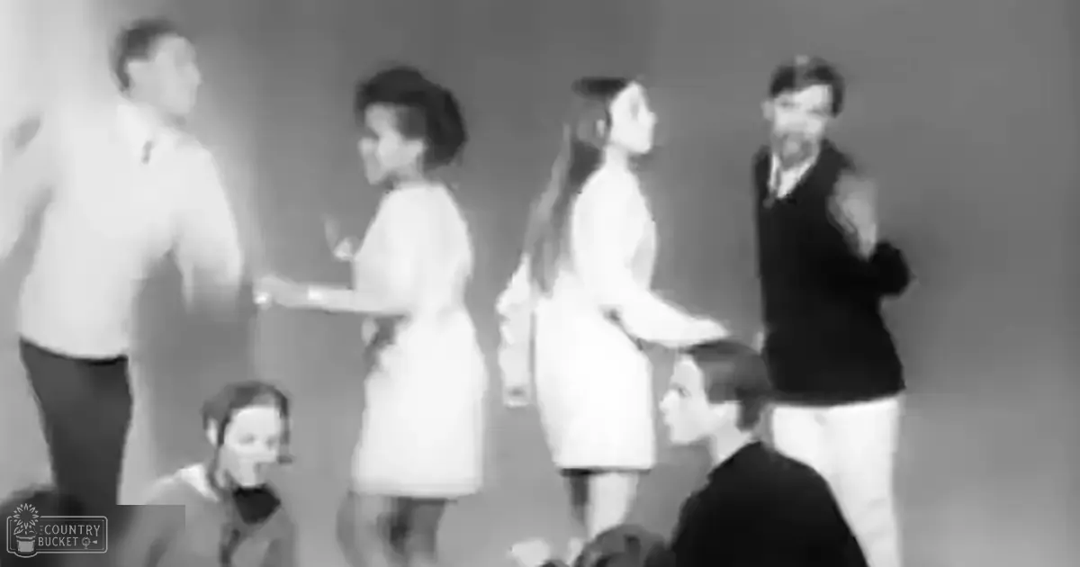 A group of individuals in a mid-20th-century indoor setting with plain walls, wearing formal and semi-formal attire from that era.