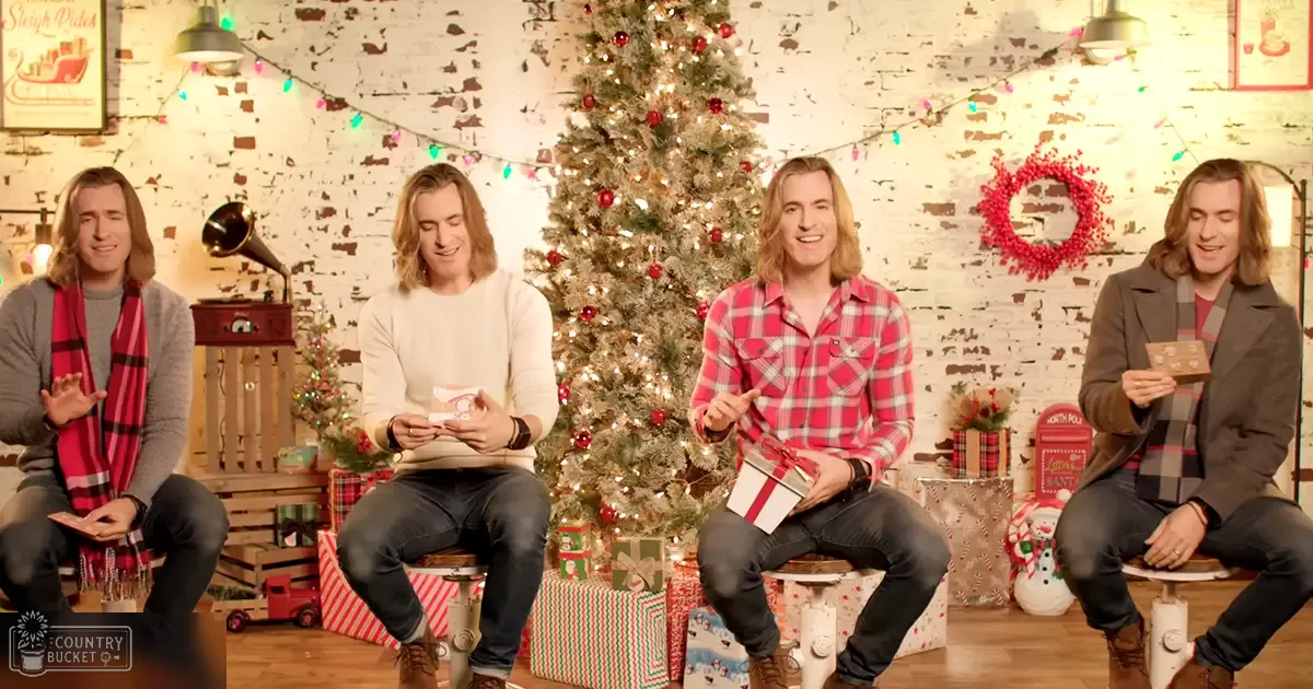 Four young adult males gather in a festive indoor setting, decorated for Christmas with lights, ornaments, and a vintage phonograph.