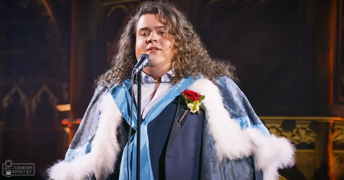 A young adult male in blue and white ceremonial attire with a red rose boutonniere is performing in an ornate church or cathedral setting.