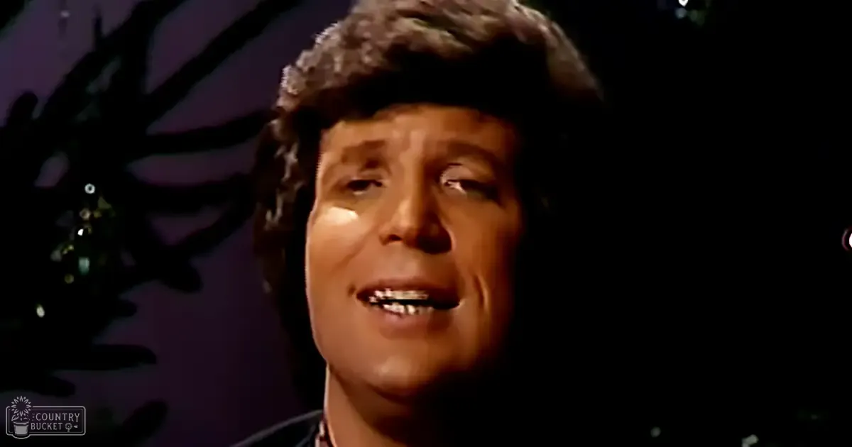 A middle-aged adult male wearing a dark-colored collared shirt indoors.