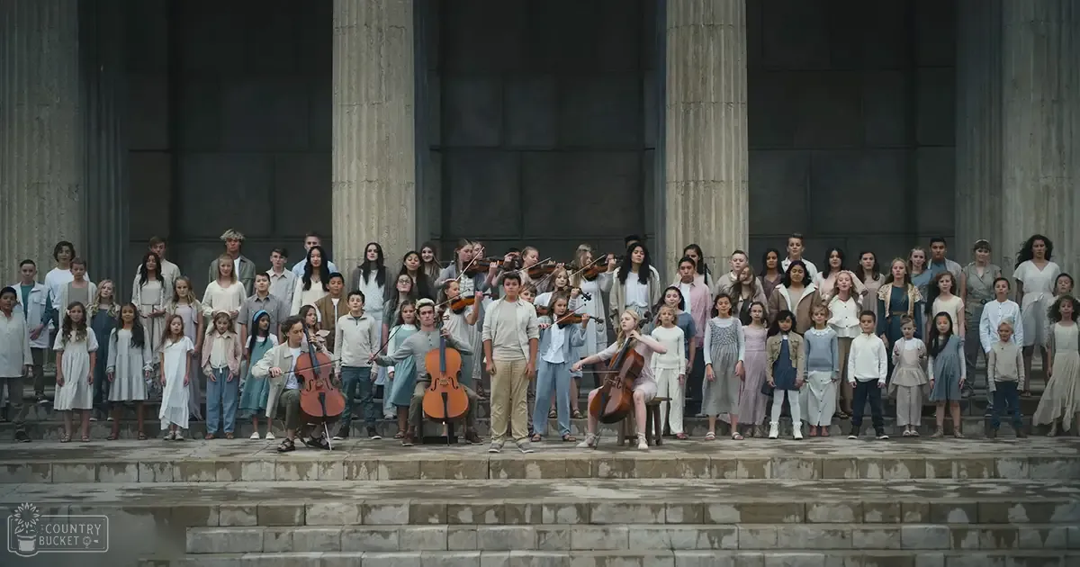 Children and young adults standing on stone steps in front of a classical-style building during an outdoor daytime event or performance with soft lighting.