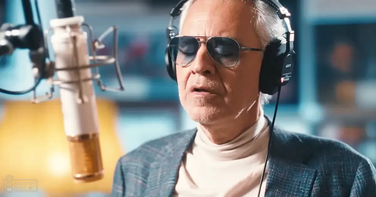 An older adult male in a recording studio, wearing a dark blue plaid blazer over a cream turtleneck, with professional microphone and Sony headphones nearby.