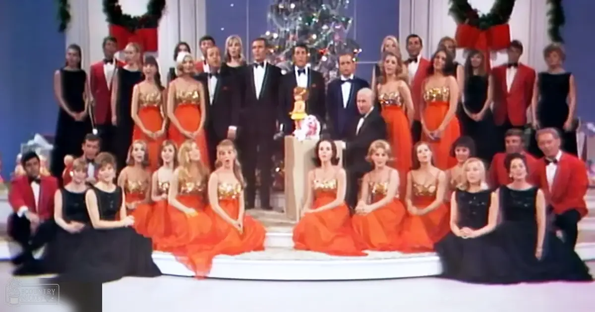 A formal group photo at an event, possibly a holiday celebration with a Christmas tree and wreaths in the background.