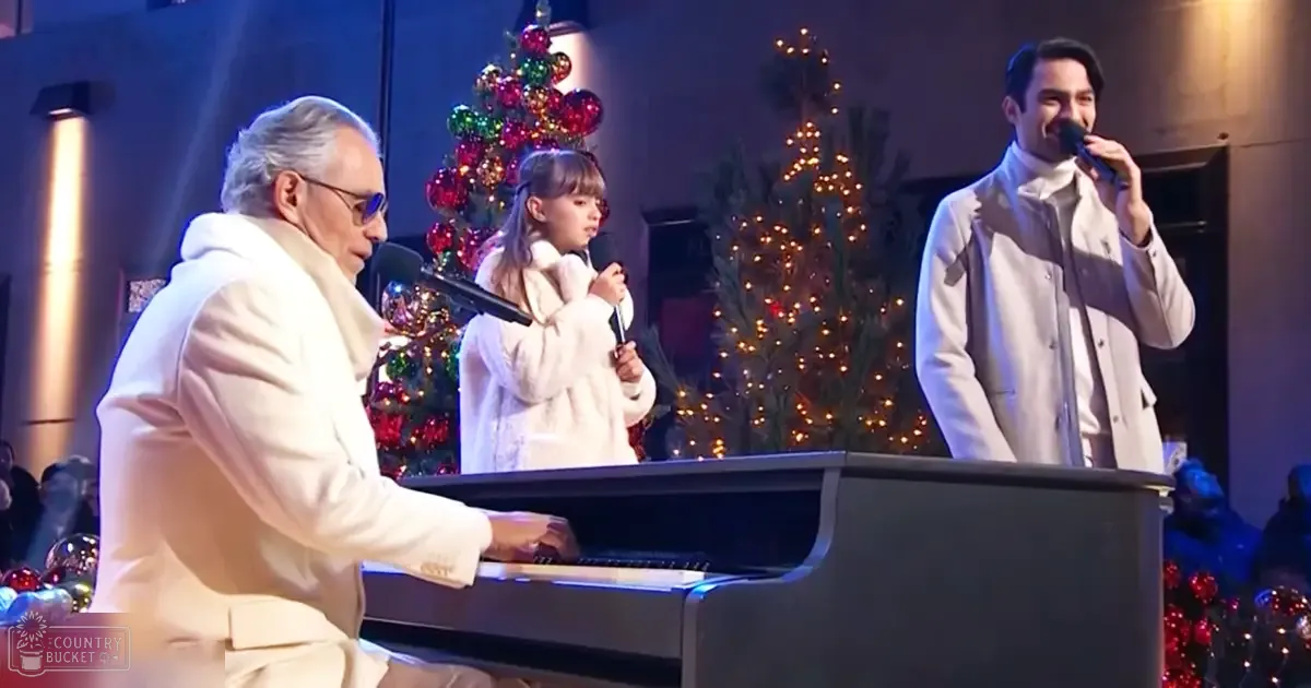 A family performs in front of Christmas trees, likely at home during the holiday season.