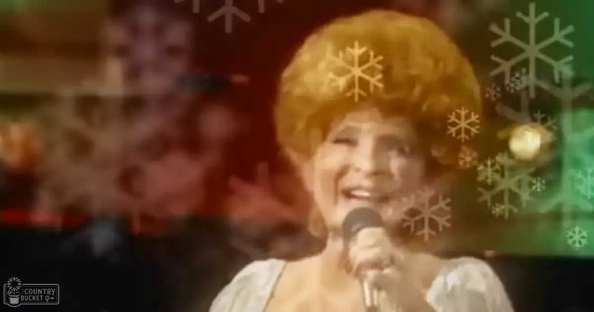 An older adult female singer in a white puffed-sleeve garment, holding a microphone with snowflake decorations indicating a holiday-themed indoor performance setting.