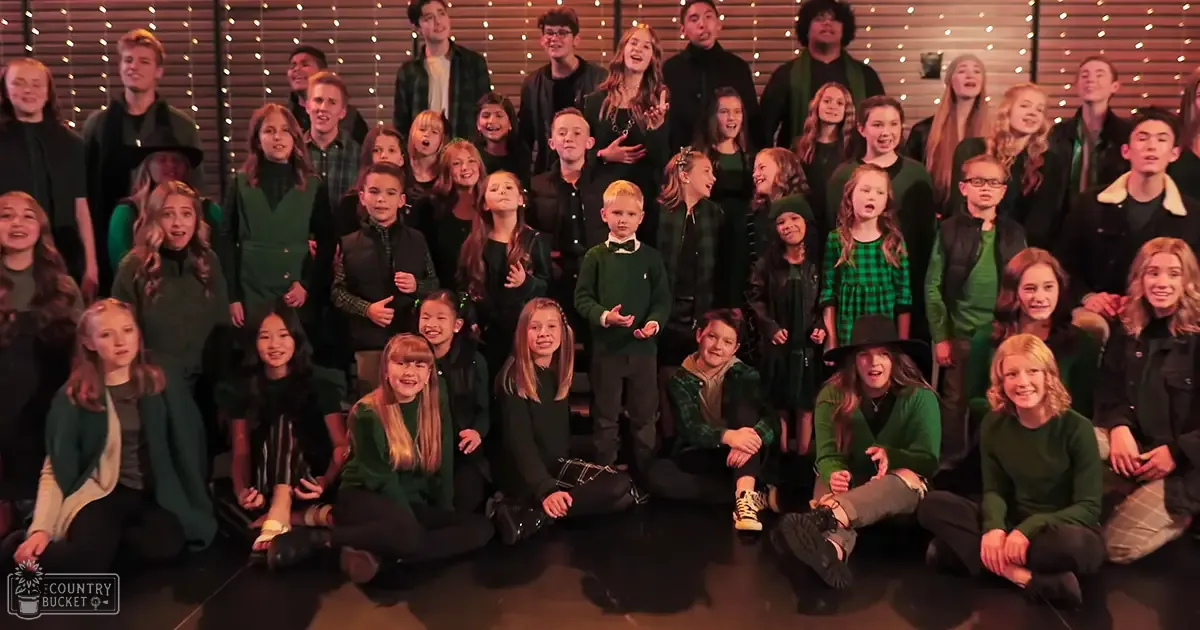 Children and young adults in a performance setting with string lights, indoor venue, cooler weather attire.