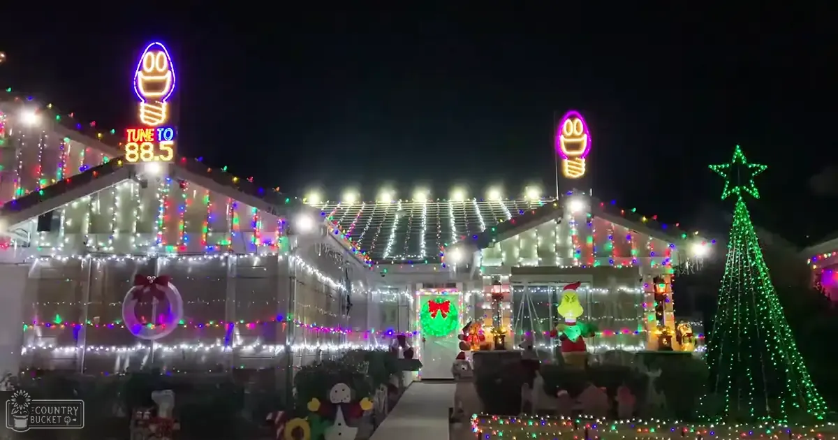 A festive Christmas display at a decorated suburban house with string lights, a Grinch figure, and various ornaments.