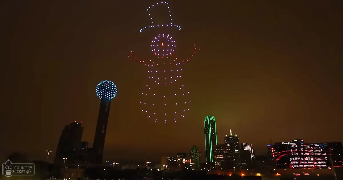 Aerial drone light show forming a figure against Dallas skyline at night with Reunion Tower illuminated
