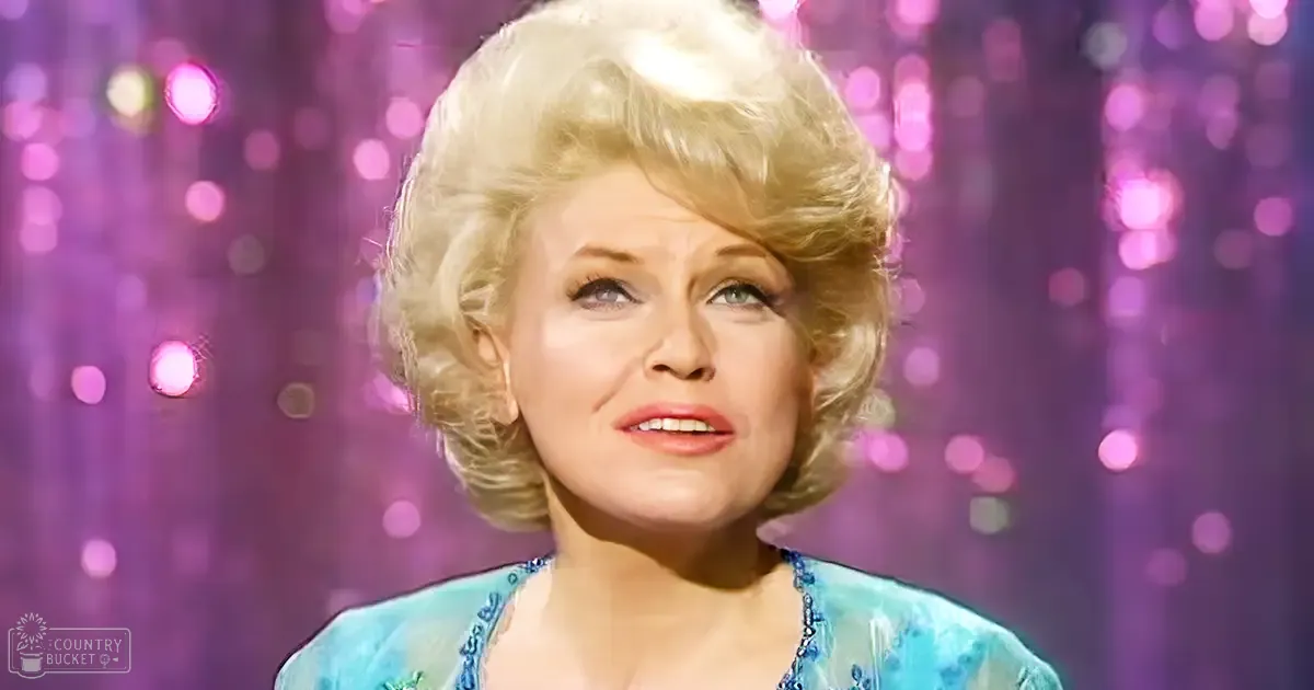 Middle-aged adult female in a festive indoor setting wearing a blue dress with intricate floral patterns during what appears to be a holiday or special event.