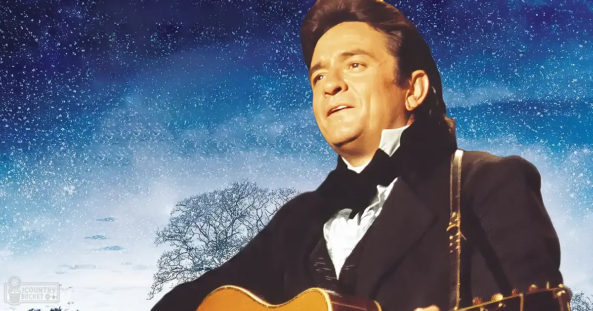 A man in a formal 19th or early 20th-century style dark-colored suit jacket stands outdoors during winter with snow-covered ground and bare trees, under a night sky with falling snowflakes.