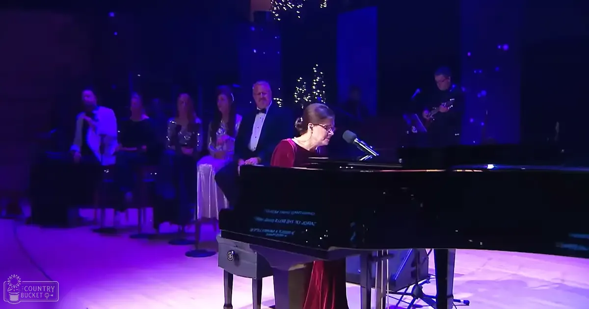 Woman playing piano with a festive holiday setting and dimly lit performance venue.