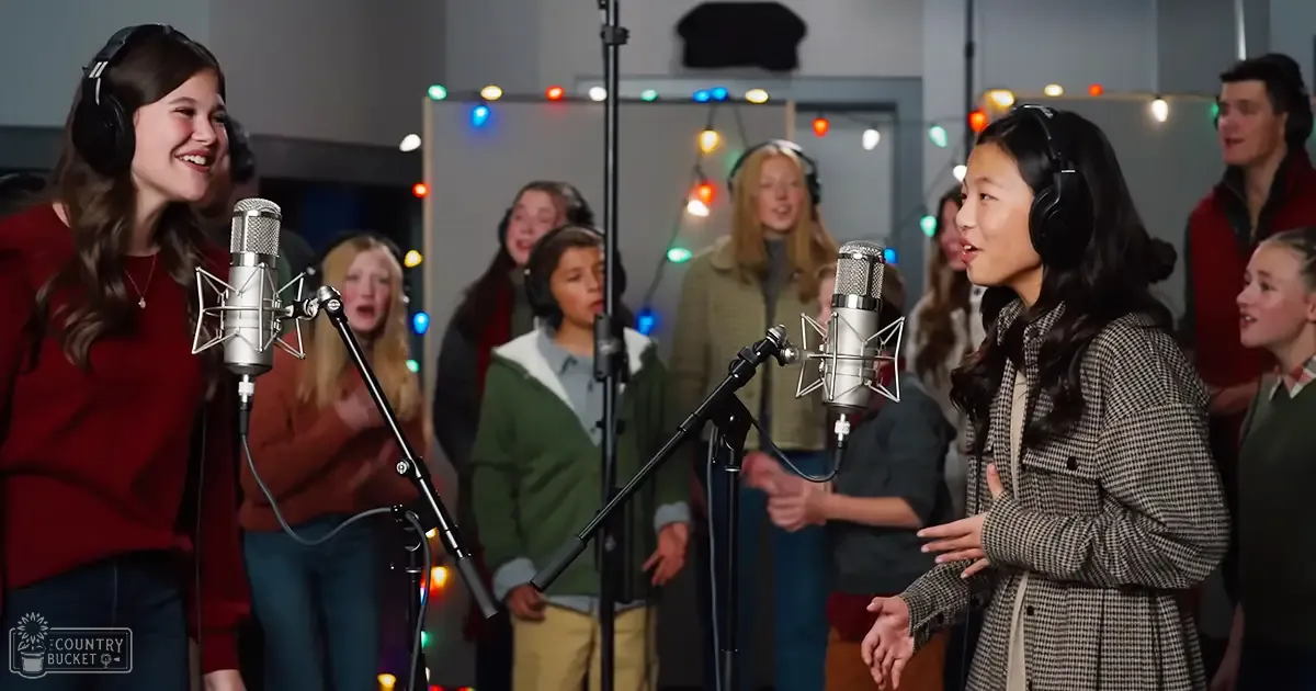 A recording studio scene with young adults, string lights suggesting a festive season, and microphones indicating a music or vocal session.
