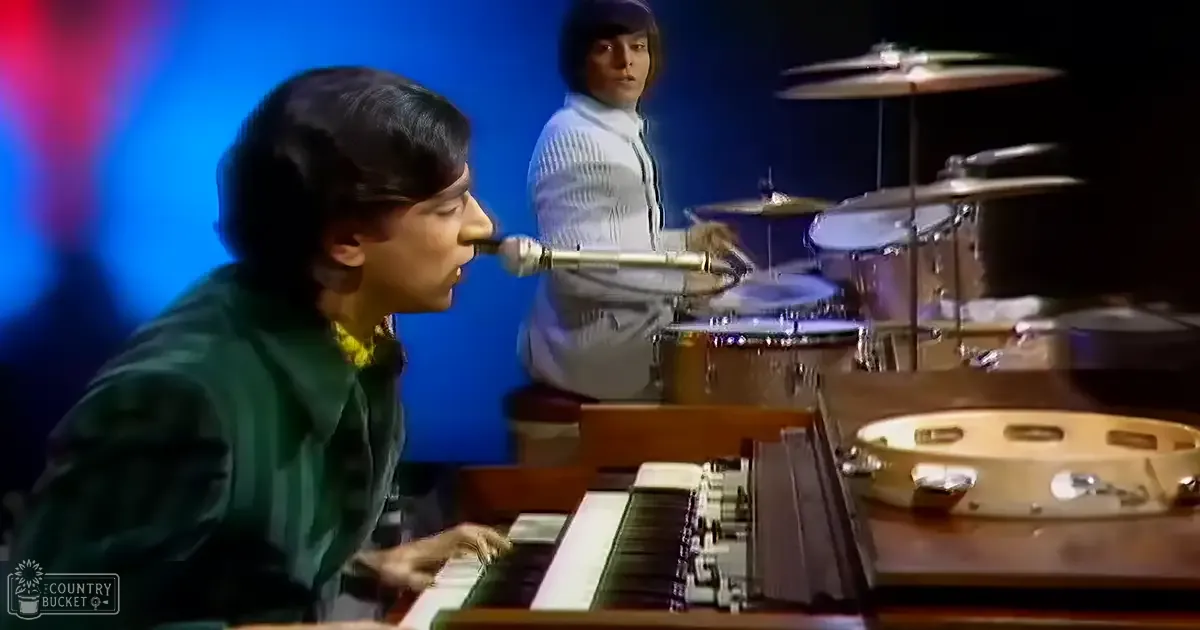 Young adult male singer performing with a drummer, vintage organ and drum set featured in an indoor music studio setting.