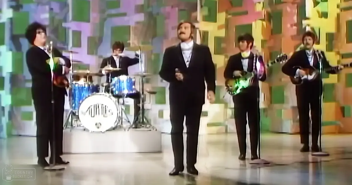 A musical performance group from the 1960s or 1970s on a stage with colorful geometric backdrop.