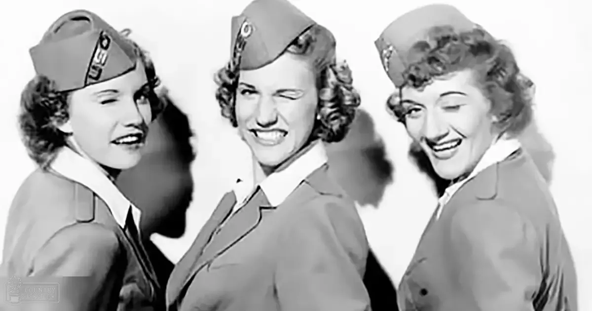 Three young adult female soldiers in World War II-era military uniforms with caps, posed indoors against a plain white background.