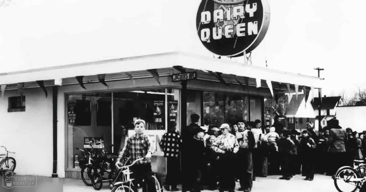 A Dairy Queen ice cream shop with a child in a plaid shirt and several adults wearing winter clothing outside, bicycles parked nearby.