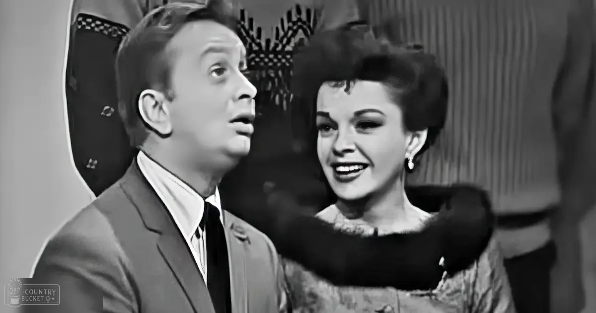 Adult male singer in a mid-20th-century indoor setting conversing with an adult female wearing a dark dress with fur collar, surrounded by furniture and soft lighting.