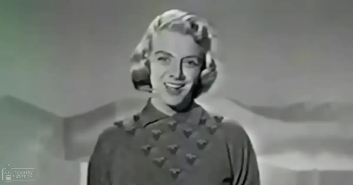 A young adult female in a dark-colored dress with heart or star patterns indoors during daytime.