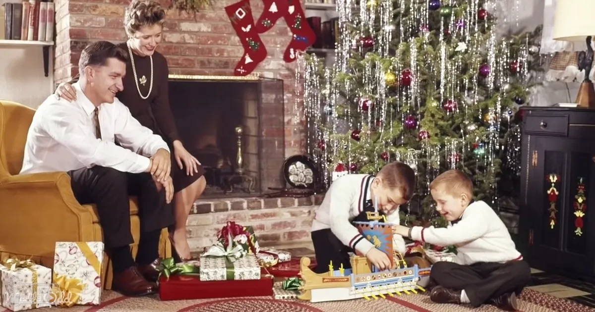 A family scene in a cozy living room decorated for Christmas during daytime with red stockings, green tree, white sweaters, black pants and yellow armchair.