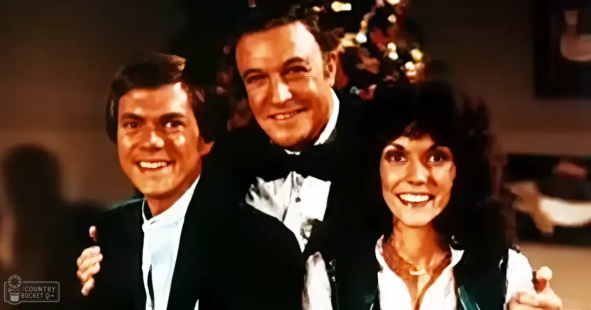 A group photo taken indoors, likely a festive setting with three adults dressed formally for what appears to be a holiday event.