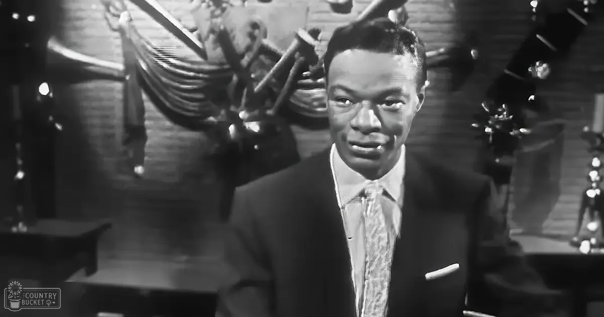 A young adult male in a dark suit jacket with a patterned tie stands indoors, likely at a jazz club, surrounded by musical instruments and bar elements under dramatic artificial lighting.