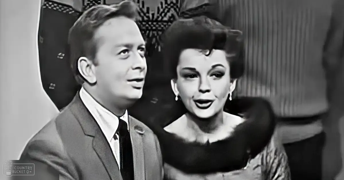 Young adult male and female dressed formally, possibly from a television show or film, with mid-20th century attire in an indoor setting.