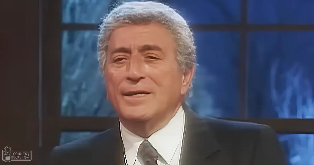 Older adult male in a studio setting with large windows showing snowy landscape, bright and even lighting typical of television studio.