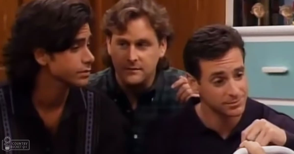A middle-aged man in an indoor setting with two younger individuals wearing casual clothing.