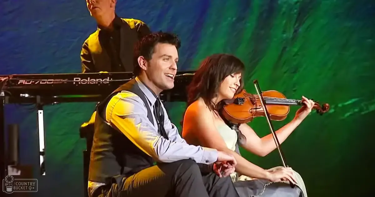 An indoor musical performance scene with a stage backdrop, bright lighting, and performers in formal attire.
