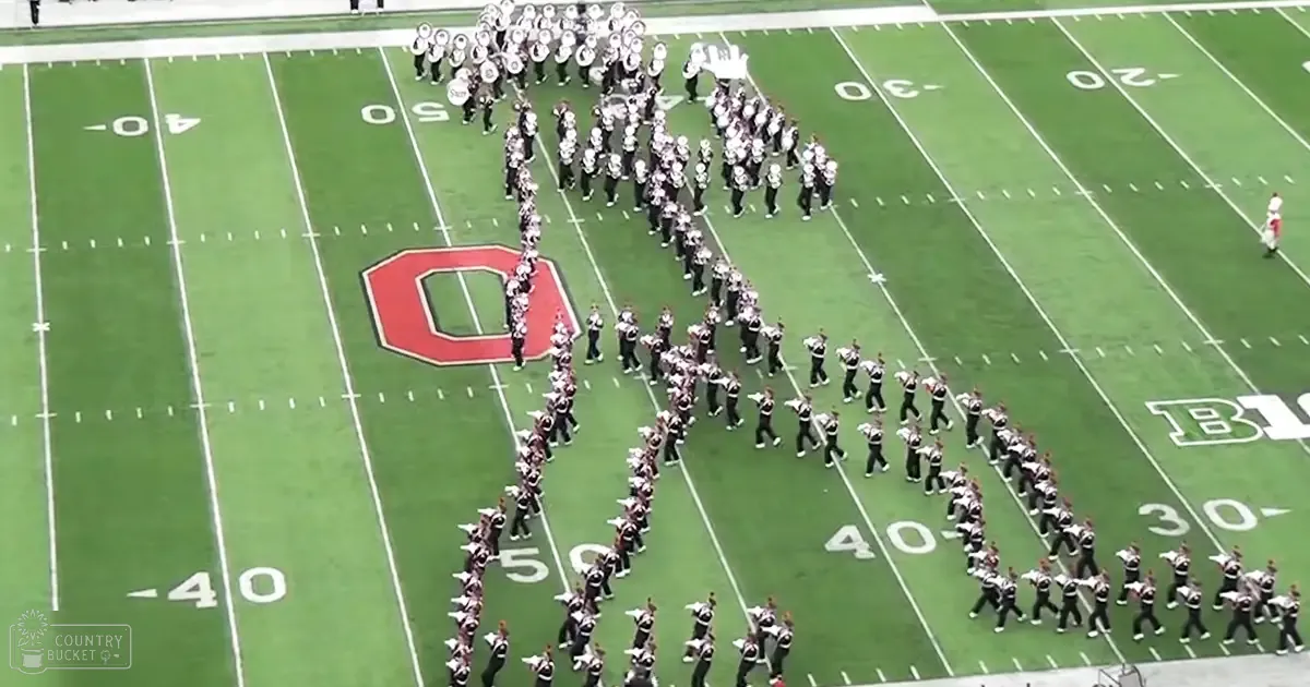 A marching band performing on a football field in fall at dusk under warm lighting conditions.