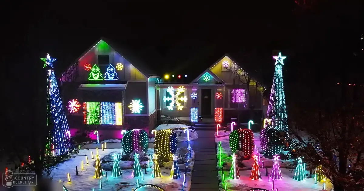 Residential neighborhood at night with houses adorned with colorful Christmas lights and decorations, illuminated by festive lighting in winter season.